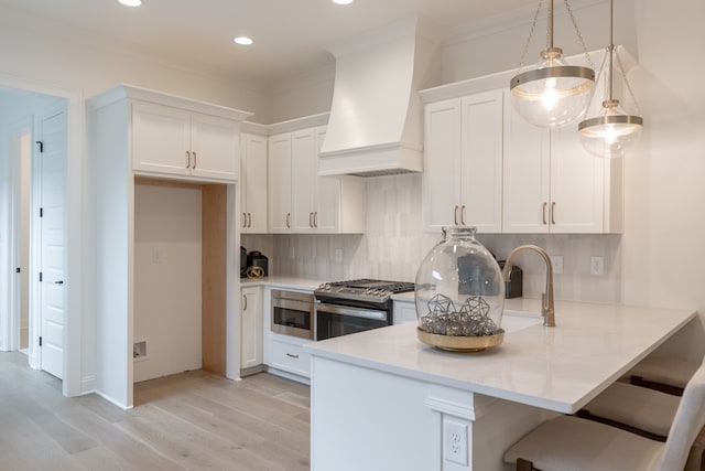 kitchen with stainless steel appliances, light hardwood / wood-style floors, pendant lighting, white cabinets, and custom exhaust hood