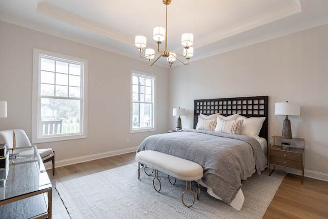 bedroom featuring a tray ceiling, multiple windows, and wood-type flooring