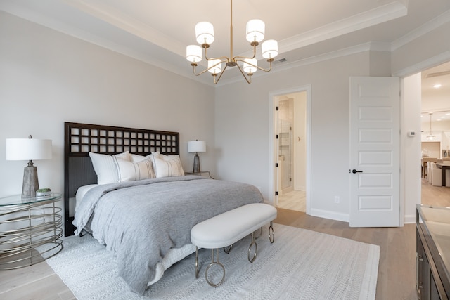 bedroom with a tray ceiling, crown molding, light hardwood / wood-style flooring, and a notable chandelier