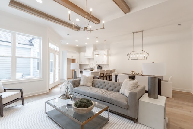 living room featuring beamed ceiling, light hardwood / wood-style flooring, and a notable chandelier