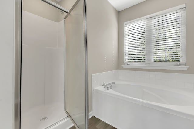 bathroom with wood-type flooring and shower with separate bathtub