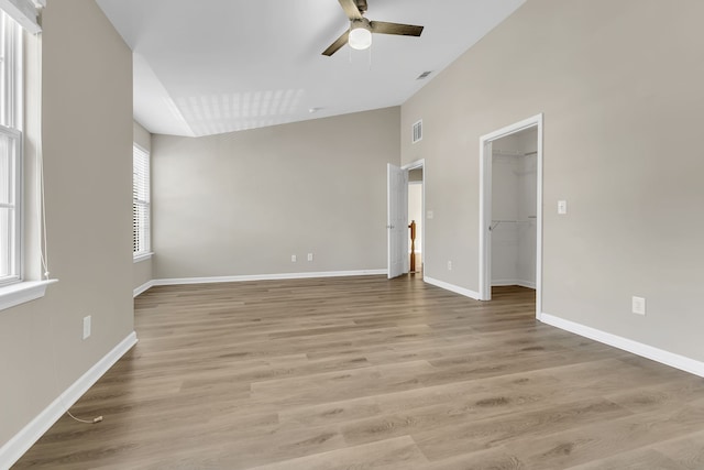 empty room with a wealth of natural light, light hardwood / wood-style flooring, and ceiling fan