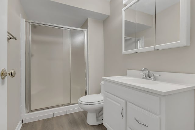 bathroom with toilet, vanity, an enclosed shower, and hardwood / wood-style flooring