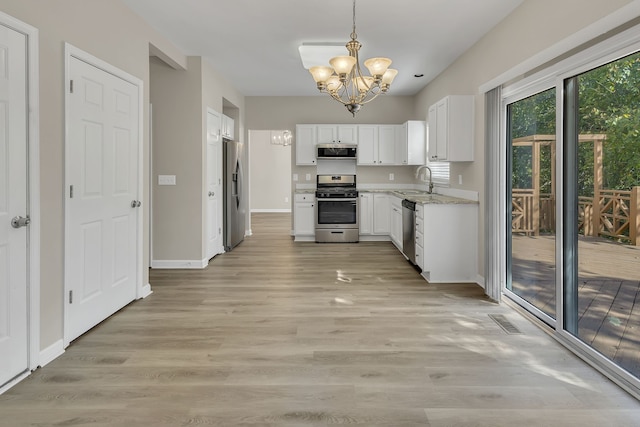 kitchen featuring white cabinets, light wood-type flooring, decorative light fixtures, and appliances with stainless steel finishes