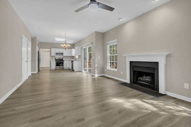 unfurnished living room featuring hardwood / wood-style flooring, ceiling fan with notable chandelier, and sink