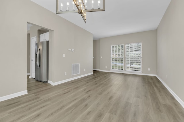 unfurnished living room with light hardwood / wood-style flooring and a chandelier