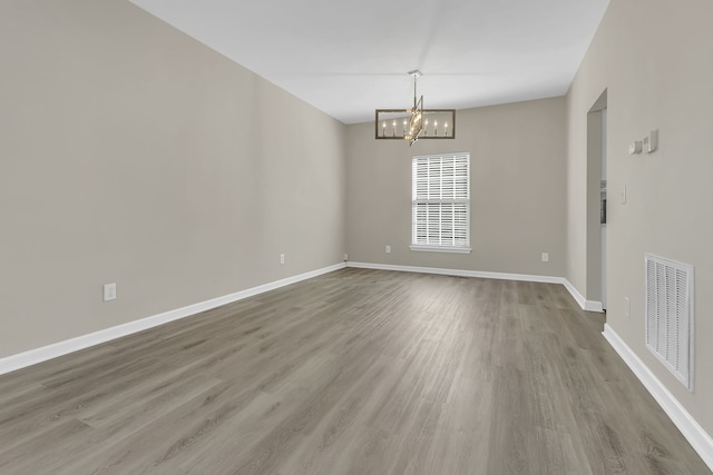 empty room featuring a chandelier and hardwood / wood-style flooring