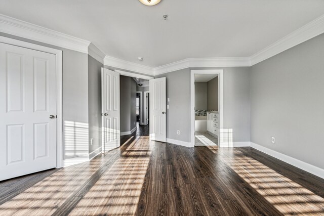 unfurnished bedroom featuring connected bathroom, dark hardwood / wood-style floors, and crown molding