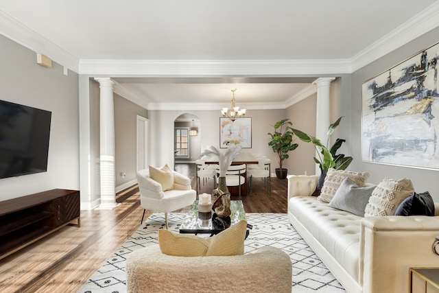 living room with a chandelier, light hardwood / wood-style floors, ornate columns, and crown molding