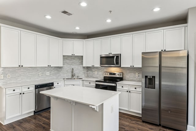 kitchen featuring white cabinets, dark hardwood / wood-style floors, a center island, and appliances with stainless steel finishes