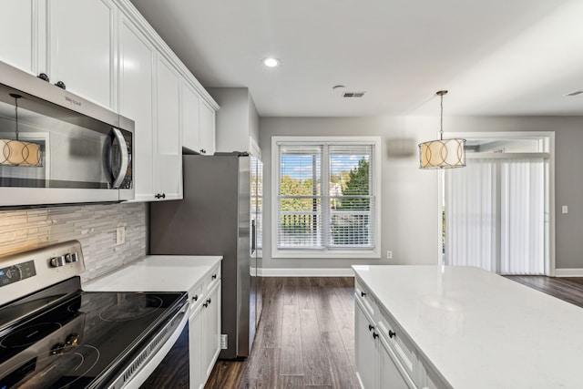 kitchen with backsplash, stainless steel appliances, dark wood-type flooring, pendant lighting, and white cabinetry