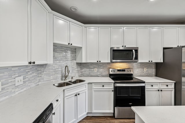 kitchen with dark wood-type flooring, white cabinets, sink, decorative backsplash, and stainless steel appliances