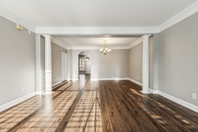 interior space featuring ornate columns, dark wood-type flooring, a notable chandelier, and ornamental molding