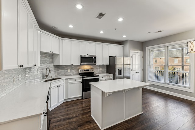 kitchen featuring white cabinetry, sink, dark wood-type flooring, a kitchen island, and appliances with stainless steel finishes