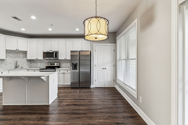 kitchen with white cabinetry, sink, dark hardwood / wood-style floors, pendant lighting, and appliances with stainless steel finishes