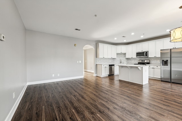 kitchen with appliances with stainless steel finishes, dark hardwood / wood-style flooring, a center island, and white cabinetry