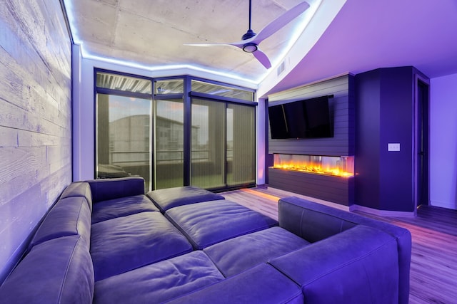 home theater featuring ceiling fan, a large fireplace, and wood-type flooring