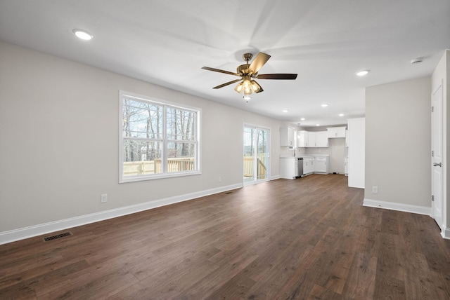 unfurnished living room with baseboards, visible vents, ceiling fan, and dark wood-type flooring