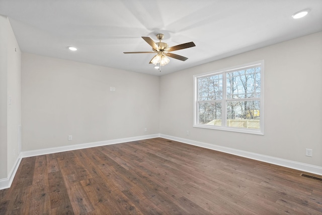 spare room featuring a ceiling fan, dark wood-style flooring, visible vents, and baseboards