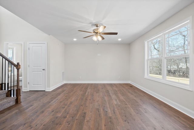 spare room featuring dark wood-style flooring, stairway, and baseboards