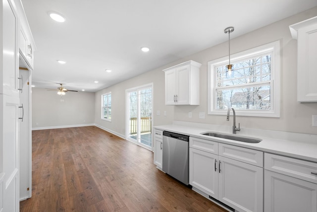 kitchen featuring dark wood-type flooring, a sink, white cabinets, light countertops, and stainless steel dishwasher