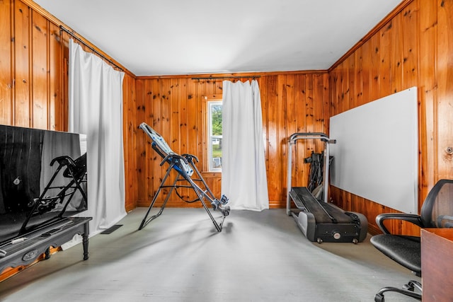 exercise room featuring wood walls and crown molding