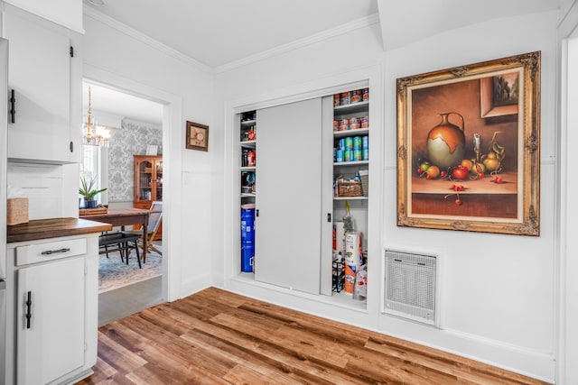 interior space featuring hardwood / wood-style flooring, built in features, ornamental molding, and a chandelier