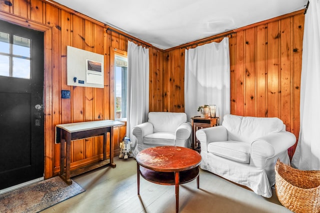 sitting room featuring wooden walls, light wood-type flooring, and a wealth of natural light