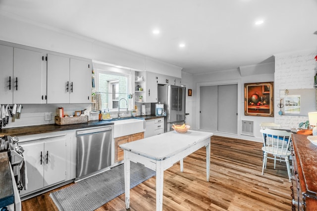 kitchen featuring white cabinetry, sink, stainless steel appliances, light hardwood / wood-style flooring, and crown molding