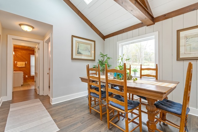 dining room with wood walls, lofted ceiling with beams, dark hardwood / wood-style floors, and wooden ceiling