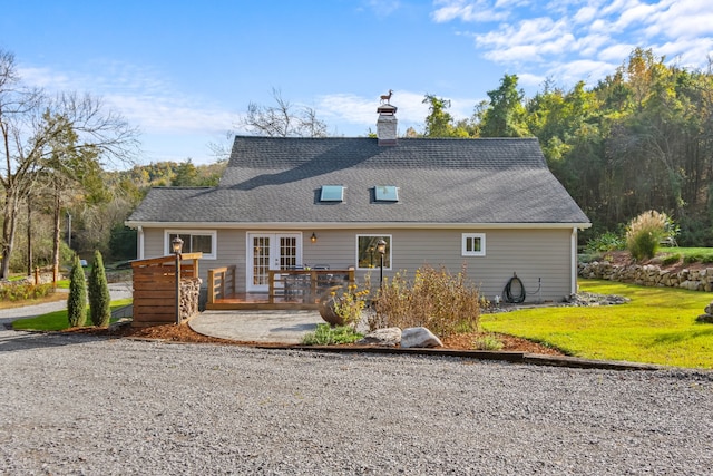 rear view of house featuring a lawn, french doors, and a deck