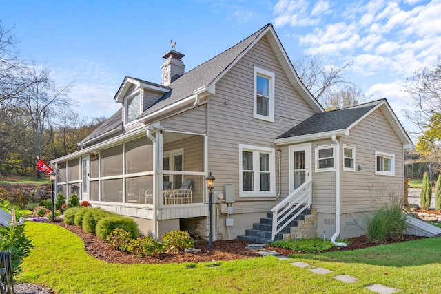 back of property with a lawn and a sunroom