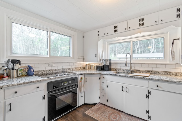 kitchen featuring black appliances, plenty of natural light, white cabinetry, and backsplash