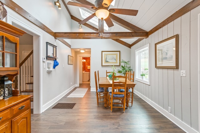 dining room featuring hardwood / wood-style floors, vaulted ceiling with beams, ceiling fan, and wooden walls