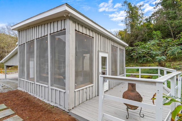 view of property exterior featuring a sunroom and a wooden deck