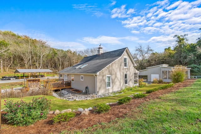 view of side of home with a lawn, an outdoor structure, and a wooden deck