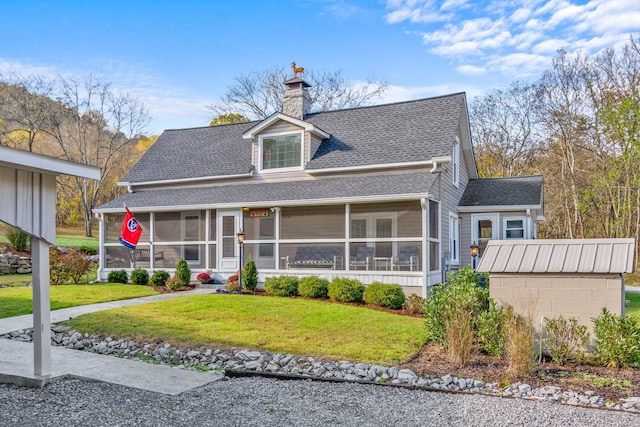 view of front of home with a front yard, a storage unit, and a sunroom