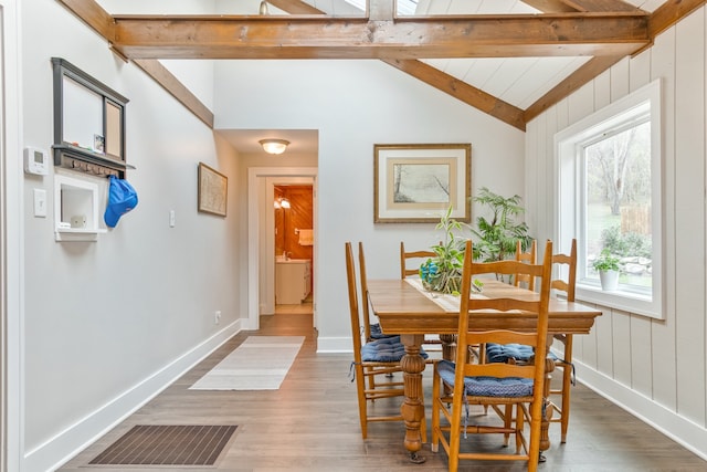 dining room featuring vaulted ceiling with beams and hardwood / wood-style flooring