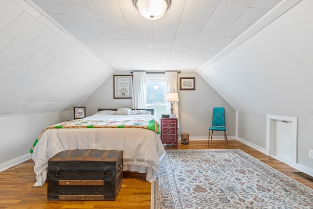 bedroom with hardwood / wood-style floors and lofted ceiling