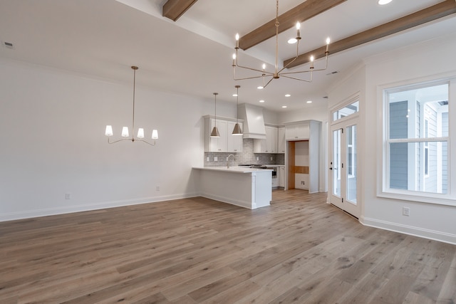 unfurnished living room featuring crown molding, sink, an inviting chandelier, light hardwood / wood-style flooring, and beamed ceiling