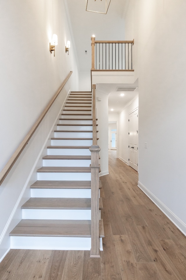 stairs featuring hardwood / wood-style flooring and crown molding