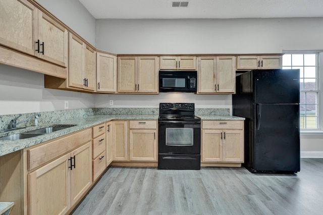 kitchen featuring light brown cabinets, black appliances, sink, light hardwood / wood-style flooring, and light stone countertops