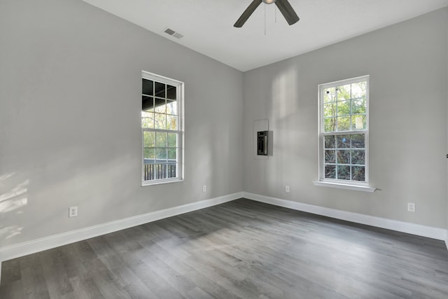 empty room featuring dark wood-type flooring, ceiling fan, and a healthy amount of sunlight