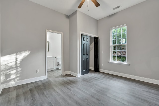 unfurnished bedroom with ensuite bathroom, ceiling fan, and wood-type flooring