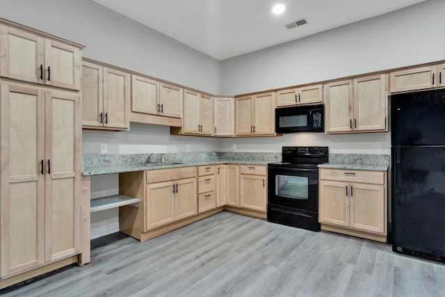 kitchen featuring light stone counters, light brown cabinets, and black appliances