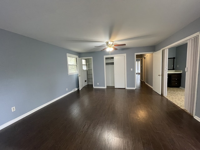 unfurnished bedroom featuring ensuite bath, ceiling fan, and dark wood-type flooring