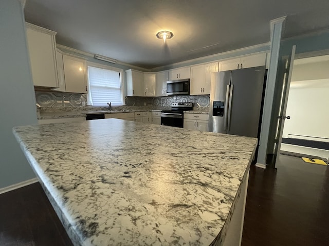 kitchen with tasteful backsplash, light stone counters, white cabinets, and appliances with stainless steel finishes