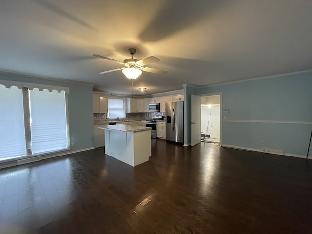 kitchen featuring a center island, dark hardwood / wood-style floors, ornamental molding, white cabinetry, and stainless steel appliances