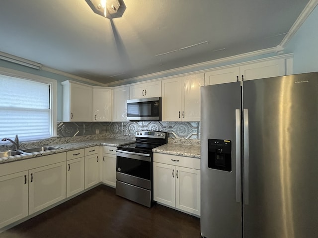 kitchen featuring light stone counters, stainless steel appliances, white cabinetry, and sink