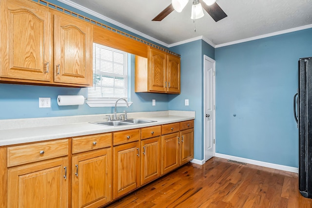 kitchen featuring ceiling fan, sink, black fridge, dark hardwood / wood-style flooring, and ornamental molding